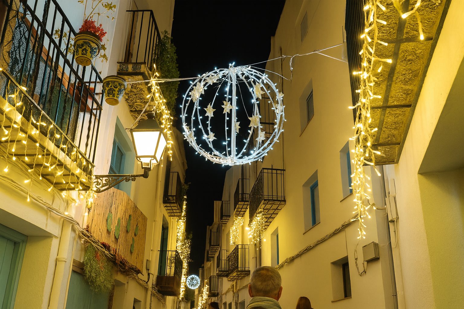 Fotografía real de una calle del casco antiguo de Peñíscola iluminada con luces de Navidad durante el encendido.